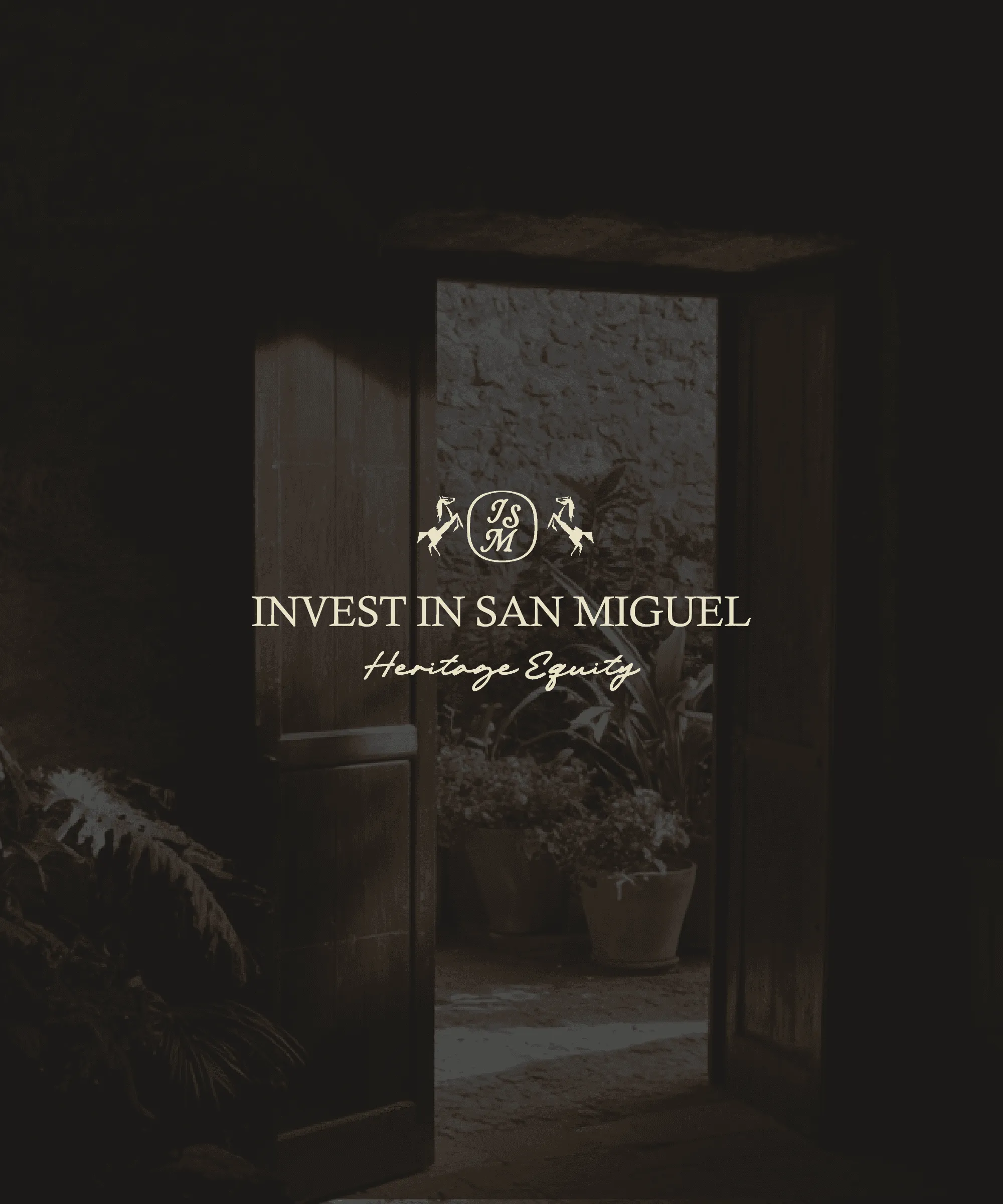 An open doorway onto a planted courtyard, carrying the Invest In San Miguel Heritage Equity mark